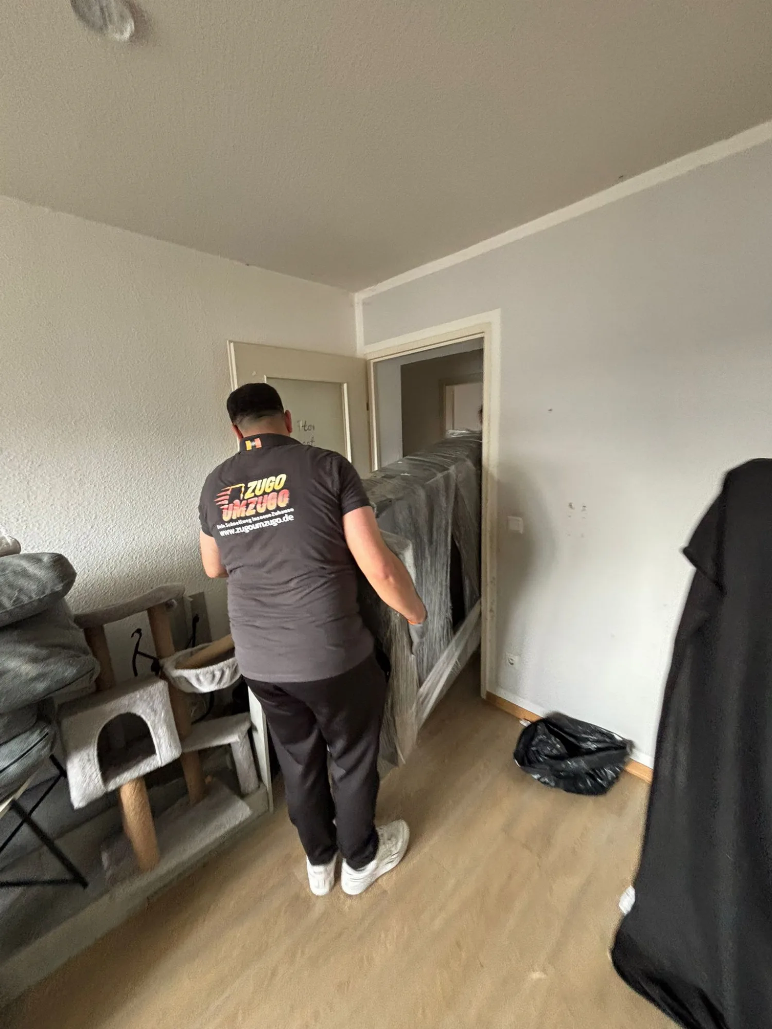 Zugo Umzugo Mitarbeiter trägt transportsicher verpackte Möbel